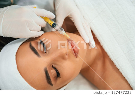 A rejuvenating shot. Woman face getting facial care by beautician hands at spa salon A rejuvenating shot. Woman face getting facial care by beautician hands at spa salon 127477225