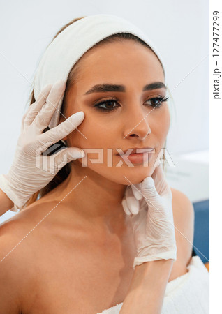 Woman face getting facial care by beautician at spa salon Woman face getting facial care by beautician at spa salon 127477299