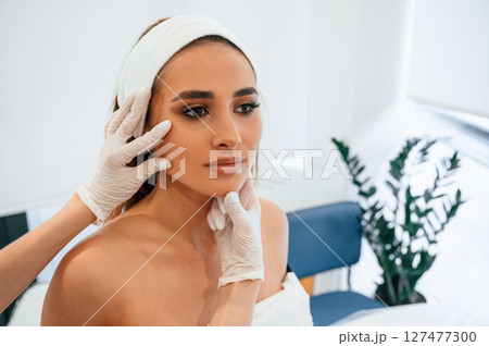 Woman face getting facial care by beautician at spa salon 127477300