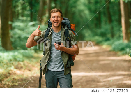 Big backpack and smartphone. Tourist in summer forest. Conception of exploration and leisure Big backpack and smartphone. Tourist in summer forest. Conception of exploration and leisure 127477596