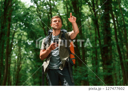 Searching the way, with smartphone for navigation. Tourist in summer forest. Conception of exploration and leisure Searching the way, with smartphone for navigation. Tourist in summer forest. Conception of exploration and leisure 127477602
