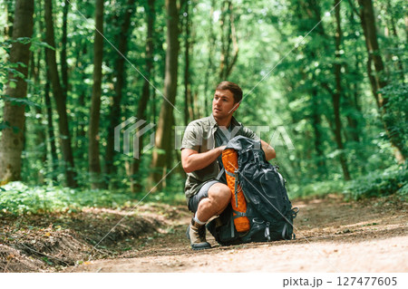 Opening the backpack. Tourist in summer forest. Conception of exploration and leisure 127477605