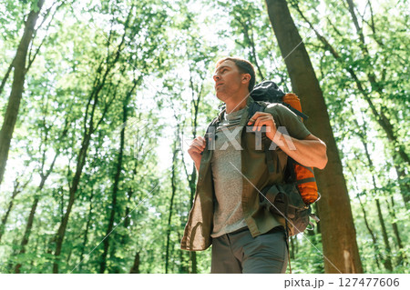 Beautiful sunlight through the trees. Tourist in summer forest. Conception of exploration and leisure Beautiful sunlight through the trees. Tourist in summer forest. Conception of exploration and leisure 127477606