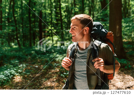 Beautiful sunlight through the trees. Tourist in summer forest. Conception of exploration and leisure Beautiful sunlight through the trees. Tourist in summer forest. Conception of exploration and leisure 127477610