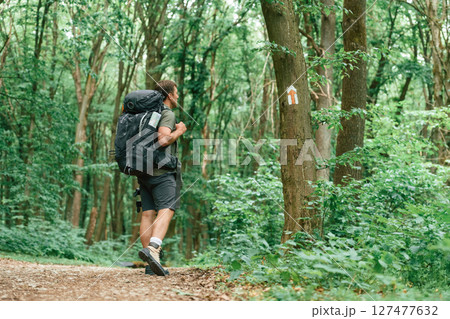 Mark with arrow on the tree that is showing the way. Tourist in summer forest. Conception of exploration and leisure 127477632