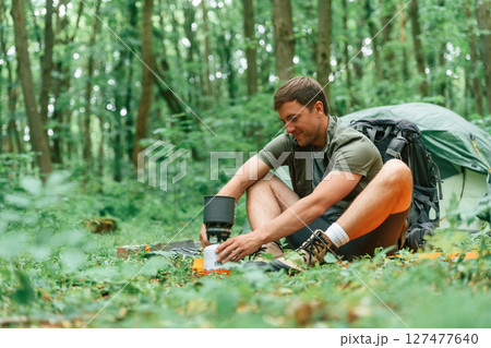 Sitting near the tent. Tourist in summer forest. Conception of exploration and leisure 127477640