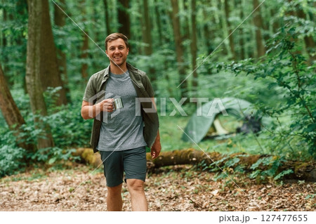 With metal cup of water. Tourist in summer forest. Conception of exploration and leisure With metal cup of water. Tourist in summer forest. Conception of exploration and leisure 127477655