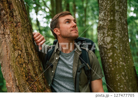 Standing between the trees. Tourist in summer forest. Conception of exploration and leisure 127477705