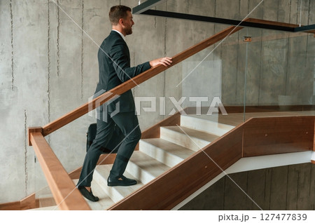 With case in hands. Man in business suit and tie is on the stairs 127477839