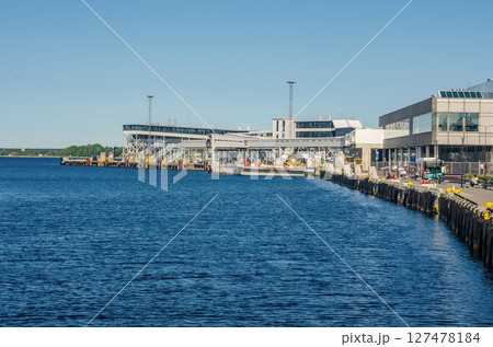 A ferry terminal with large buildings and structures along a calm blue sea. High quality photo 127478184