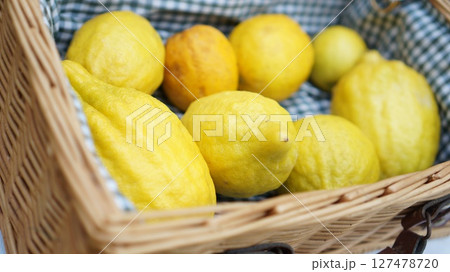 Freshly harvested lemons in a woven basket on a checkered cloth 127478720