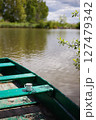 A tranquil scene of a green rowboat on still water, with a simple enamel mug resting on the wooden seat 127479342