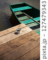 A rustic wooden dock by the water features a single enamel mug of coffee, offering a tranquil lakeside scene 127479343