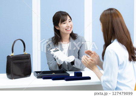 買取業者 窓口で査定をしている女性 買取業者 窓口で査定をしている女性 127479899
