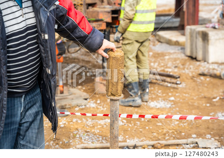 Man cutting and cleaning soil sample for laboratory analysis. Preparation of core material for geotechnical testing and scientific evaluatio 127480243