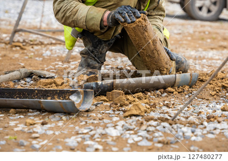 Man cutting and cleaning soil sample for laboratory analysis. Preparation of core material for geotechnical testing and scientific evaluatio 127480277