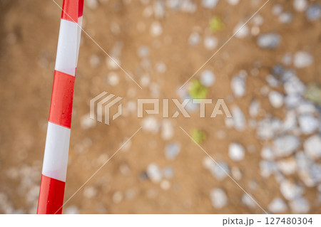 Red and white warning tape stretched across a restricted construction area. Symbol of safety measures, site control, and hazard prevention. 127480304