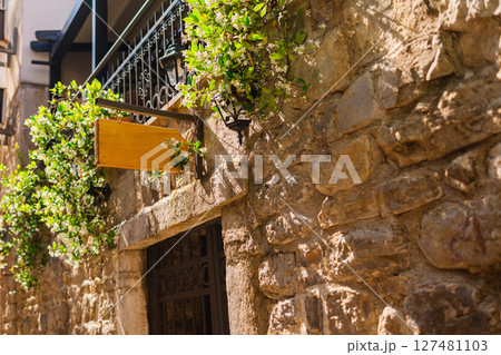 Blank signboard on stone building wall in Mediterranean alley. Concept of urban signage, empty brand space, and local European architecture. Copy space 127481103