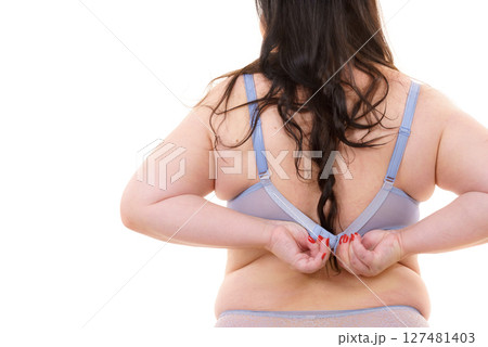 Woman back view putting on her bra lingerie. 127481403