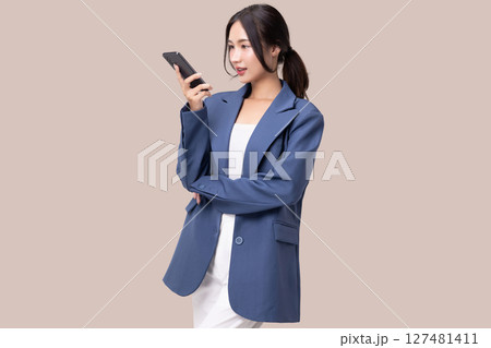Portrait of happy young business woman talking with AI on smartphone isolated on brown background. 127481411