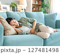 生理痛で体調不良の女性がソファで休む様子 127481498