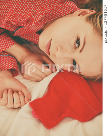 Woman sleeping with warm red hot water bottle 127481617