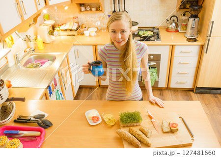 Woman in kitchen holding knife making healthy sandwich Woman in kitchen holding knife making healthy sandwich 127481660
