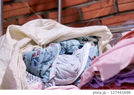 Colorful Fabric Rolls in a Sack Against Textured Brick Wall 127481696