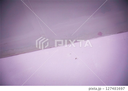 Close-up of a damaged purple painted wall and ceiling corner 127481697
