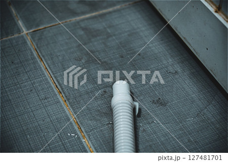 White plastic pipe on a tiled dark floor White plastic pipe on a tiled dark floor 127481701