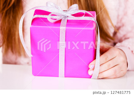 Female hands holding pink gift box with ribbon Female hands holding pink gift box with ribbon 127481775