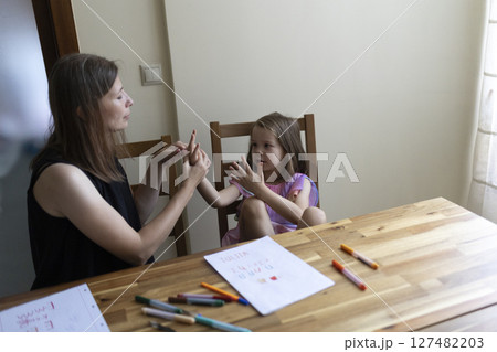 Mother teaching numbers to her daughter using finger counting method 127482203