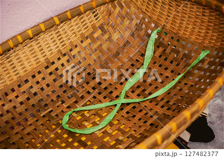 Traditional woven natural fiber basket with a green plastic strap 127482377