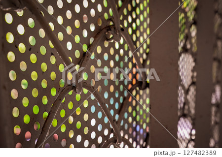 Perforated metal sheet with colorful blurred light background 127482389
