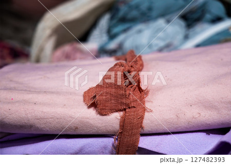 Close-up of stacked colorful fabrics with a frayed textile strip Close-up of stacked colorful fabrics with a frayed textile strip 127482393