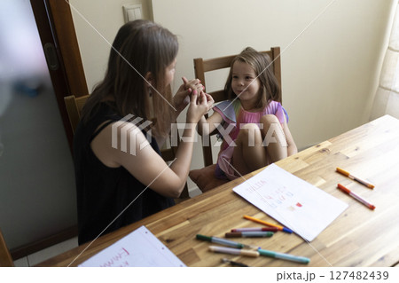 Teacher helping young girl student learning sign language at home 127482439