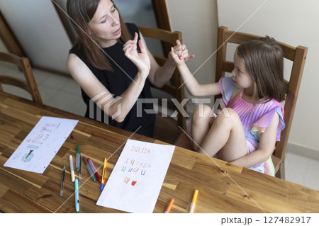 Teacher helping young girl with sign language at home 127482917