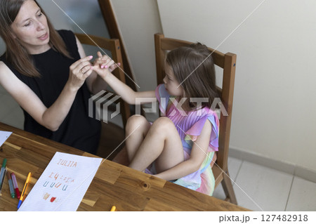Teacher helping young girl student learning writing skills at home 127482918