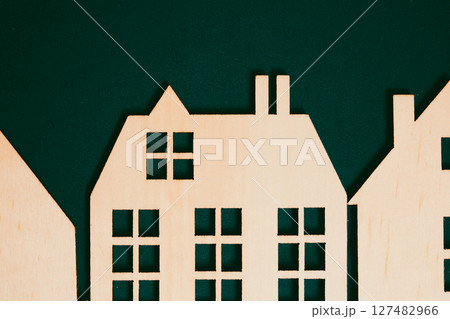 Decorative wooden house with sloping roof, smokestack on dark background. Toy rural wooden cottage. Real estate for sale. Residential properties. Home 127482966