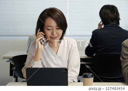 ビジネスウーマン、電話で相談をする 127483454