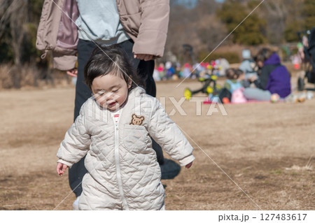 【相模原市立麻溝公園の芝生広場で遊ぶ1歳児とおかあさん】 127483617
