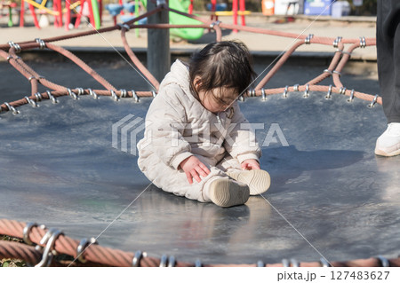 【相模原市立麻溝公園の子どもの広場のトランポリンでママと遊ぶ1歳児】 127483627