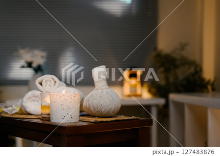 Rolled white towels, flower, and candle arranged on a table in a serene spa Rolled white towels, flower, and candle arranged on a table in a serene spa 127483876