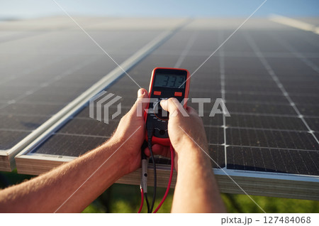 Holds a thermal imager. Close up view of man that is doing operating and maintenance in solar power plant Holds a thermal imager. Close up view of man that is doing operating and maintenance in solar power plant 127484068