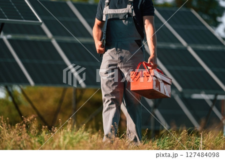 Walking and holding repair toolbox. Close up view of man that is doing maintenance in solar power plant Walking and holding repair toolbox. Close up view of man that is doing maintenance in solar power plant 127484098