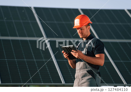 Tablet in hands. Man is doing operating and maintenance in solar power plant 127484110