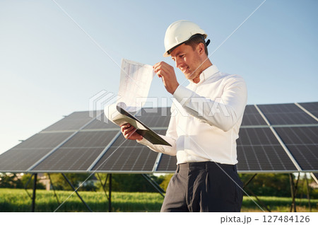 Notepad with document is in hands. Man is doing operating and maintenance in solar power plant 127484126