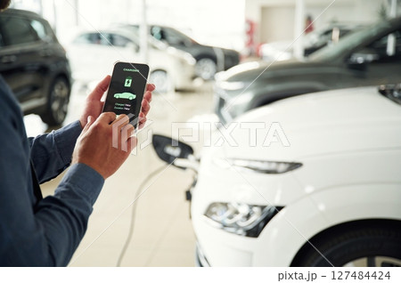 Information of charging process. Close up view of man that is with electrical car 127484424