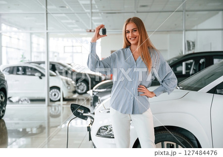 Keys in hands. Beautiful woman is indoors with the modern car Keys in hands. Beautiful woman is indoors with the modern car 127484476
