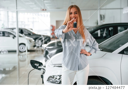 Keys in hands. Beautiful woman is indoors with the modern car Keys in hands. Beautiful woman is indoors with the modern car 127484477